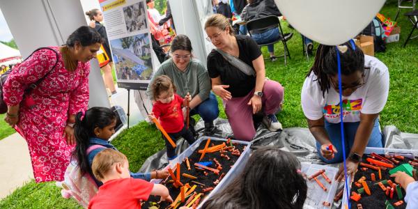 Children digging into bins to unravel pieces of toy buildings at Maryland Day.