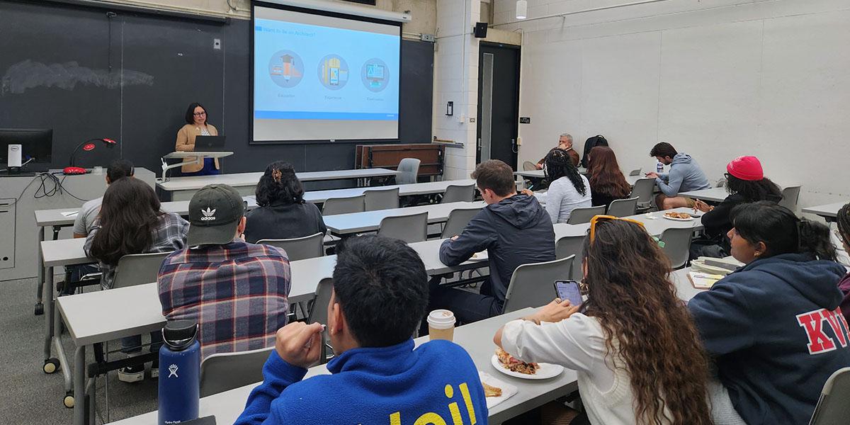 Students in a classroom with someone presenting slides